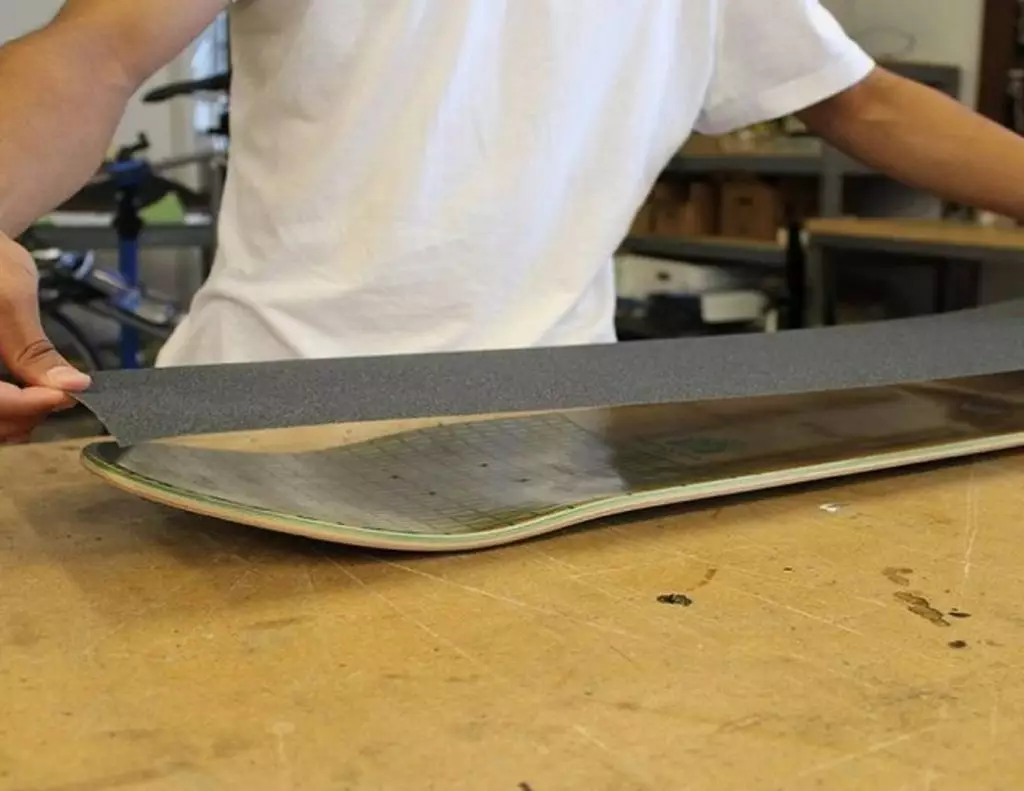 Lixa de skate sendo instalada num skate durante a montagem