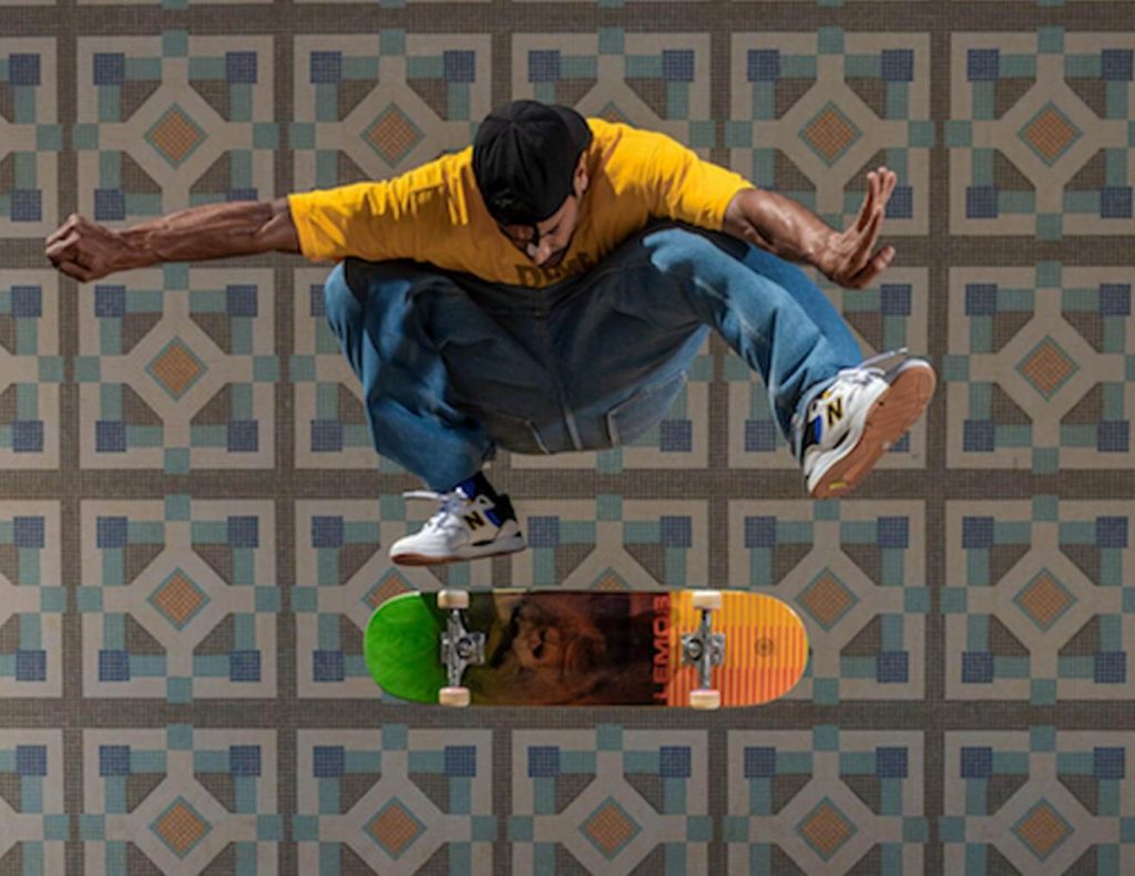 Homem dando uma manobra de skate, vestindo as cores da skateshop Prince Of Streets